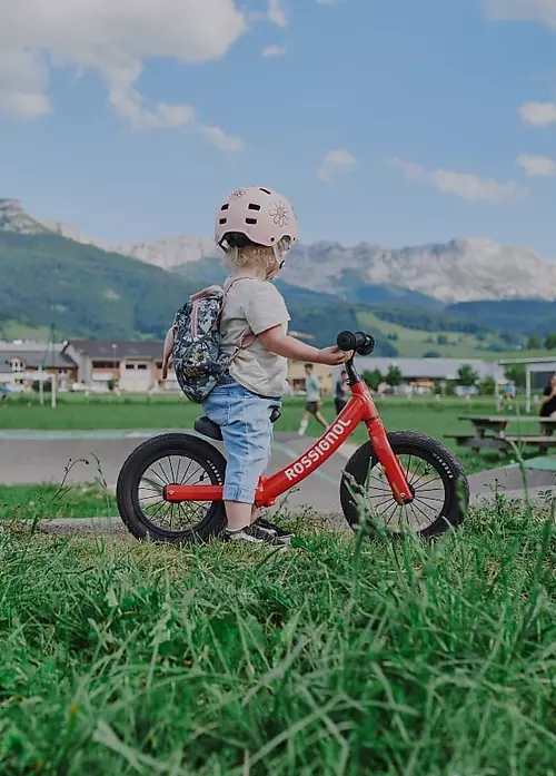 Copil pe bicicletă Rossignol cu munții în fundal